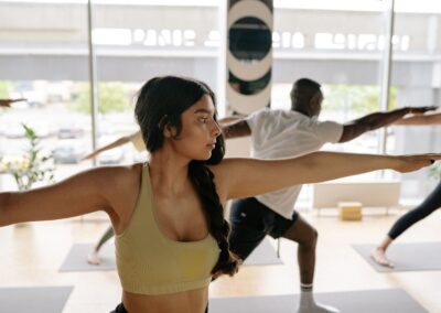 Diverse group practicing yoga warrior pose indoors for fitness and wellness.